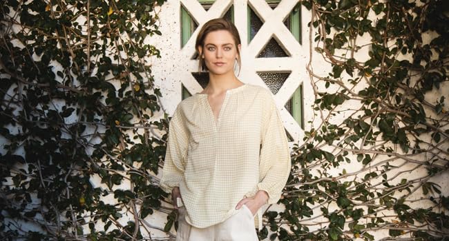 Model standing in a garden with a v-neck blouse and shorts